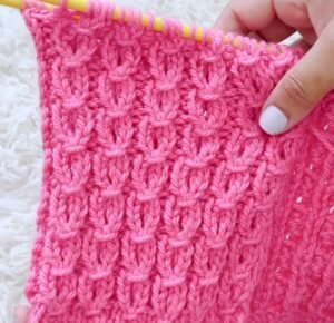 Amostra de ponto de tricô em fio rosa nas agulhas